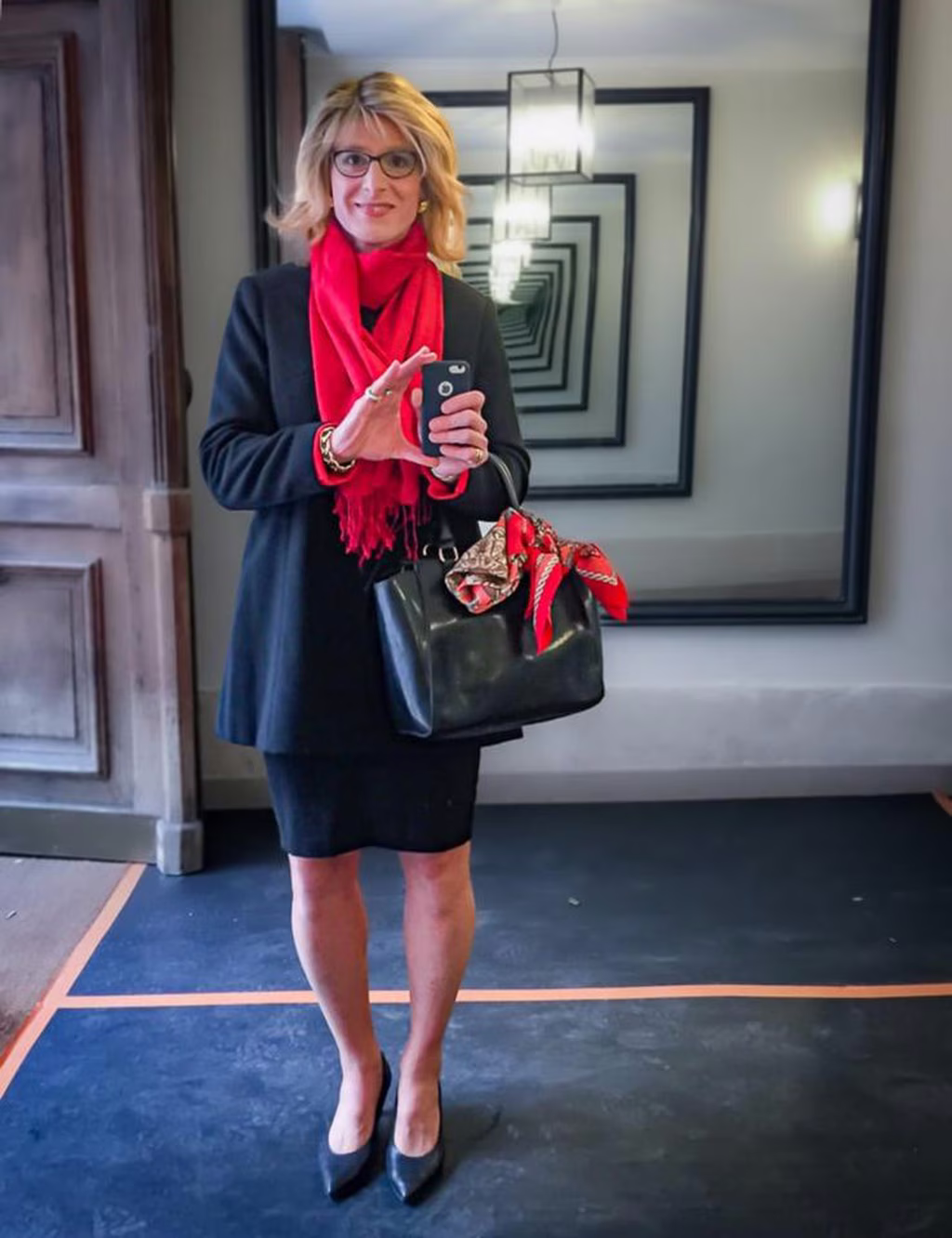 L'écharpe rouge de Glawdys apporte une touche de couleur vibrante qui contraste magnifiquement avec son manteau noir, créant un look à la fois audacieux et raffiné