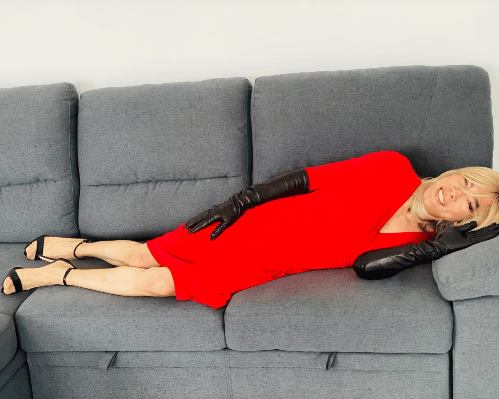 Cette image représente un moment de joie pure et de célébration de soi. La couleur rouge de la robe symbolise la passion et la force, tandis que le sourire de Laure reflète une liberté nouvelle et une affirmation joyeuse de son identité