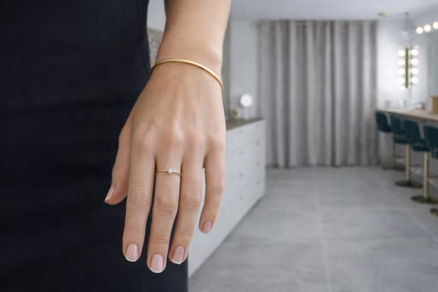 Main avec bague fine dorée, petit bracelet jonc et ongles nude dans le studio Transbeauté