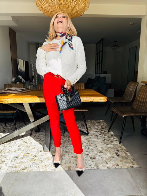 Freda travesti élégante avec pantalon rouge et maquillage féminin après sa transformation chez Transbeauté
