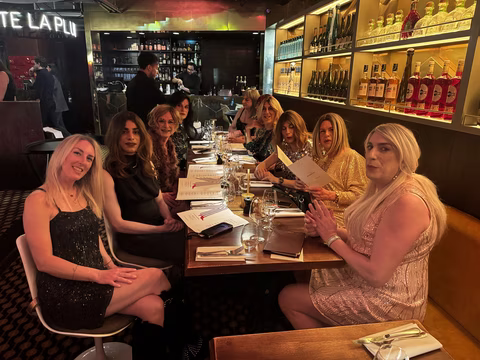 Participantes Transbeauté réunies autour d’une grande table dans un restaurant festif à Paris, pendant la soirée du 16 avril, en tenues élégantes et maquillages soignés