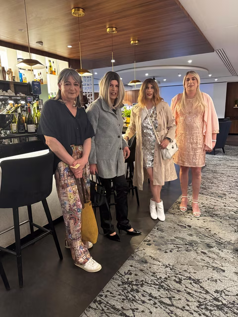 Quatre participantes Transbeauté posent dans un hôtel parisien avant la soirée du 16 avril, en tenues élégantes et festives, avec maquillage soigné et looks féminins affirmés