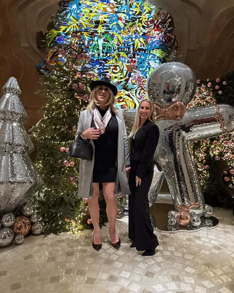 Jennifer et Deborah posent devant une décoration festive et élégante, illuminée par des sapins scintillants et des ornements brillants. Une ambiance chic et chaleureuse pour célébrer les fêtes