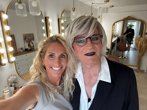 Jennifer pose fièrement avec une cliente élégante au maquillage audacieux, dans un studio de mise en beauté.